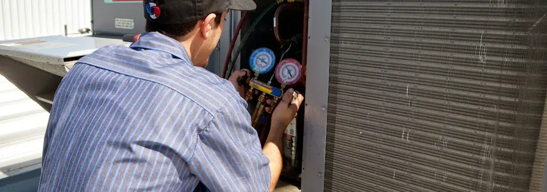 HVAC technician servicing a condenser unit in Pearl